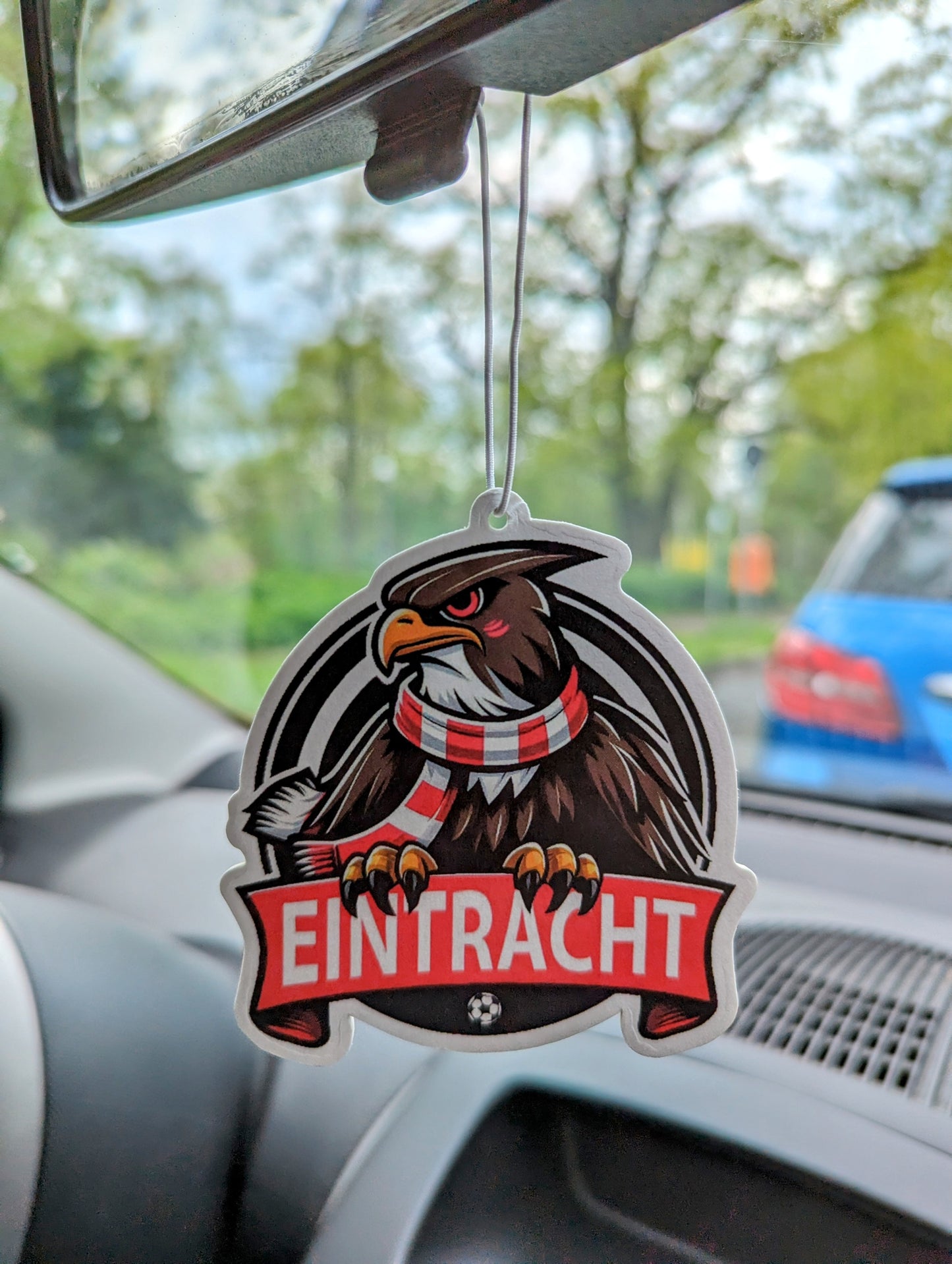 Auto Duftbaum Adler mit rot und weißem Schal krallt sich an einem roten Banner fest und hängt am Auto Rückspiegel