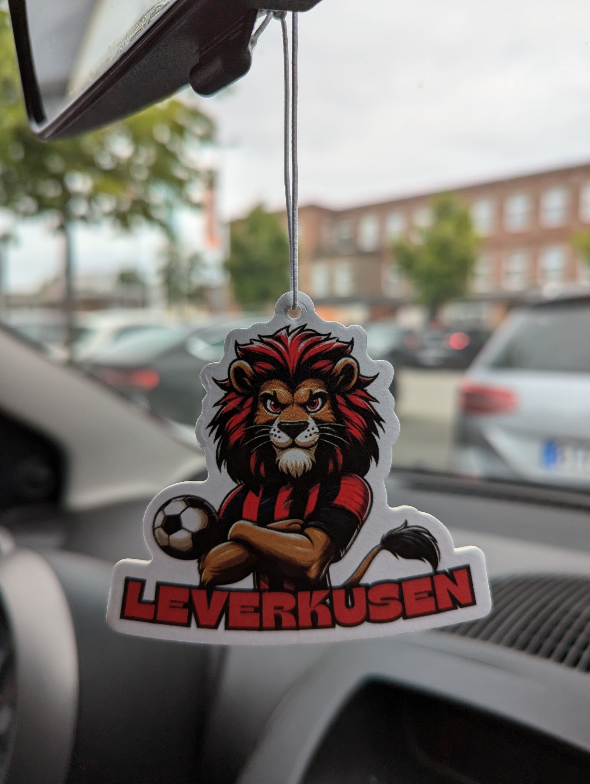 Auto Duftbaum Fußball Löwe mit einem schwarz roten Trikot und dem Schriftzug Leverkusen hängt am Auto Rückspiegel