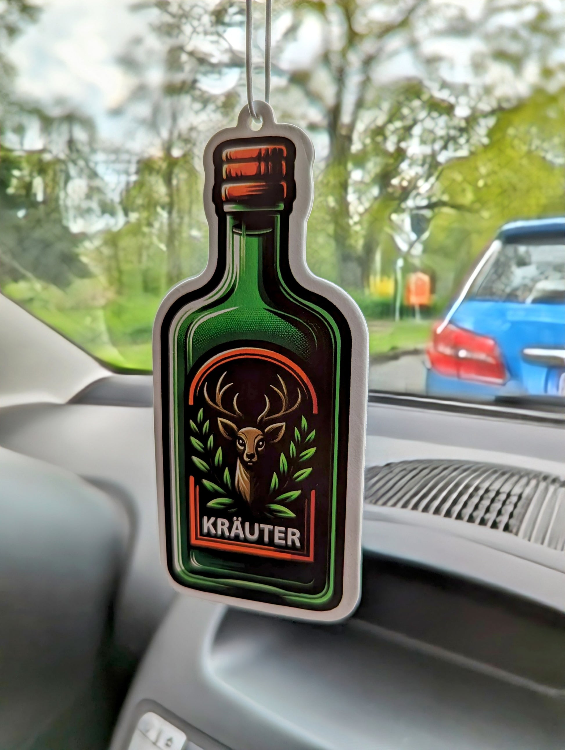 Auto Duftbaum einer Kräuter Schnapsflasche mit einem Reh darauf abgebildet, hängt am Auto Rückspiegel