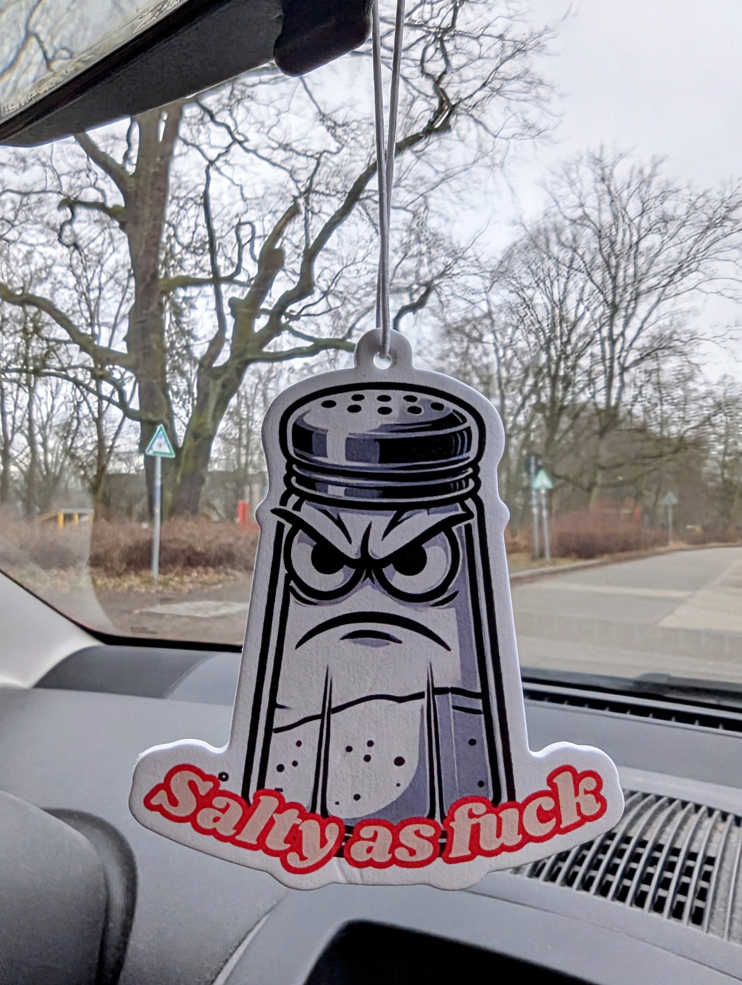 Auto Duftbaum in Form eines Comic-Salzstreuers mit grimmigem Gesicht und rotem Schriftzug „Salty as fuck“, Lufterfrischer fürs Auto mit witzigem Motiv, origineller Autoduftbaum als Spaß-Artikel und Geschenkidee.