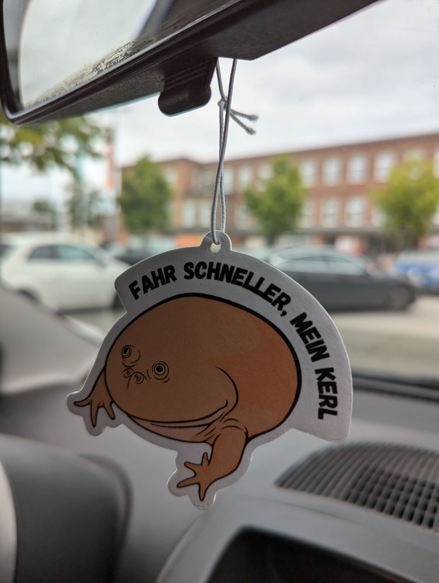 Auto Duftbaum Mittwochsfrosch Nummer zwei hängt am Auto Rückspiegel.