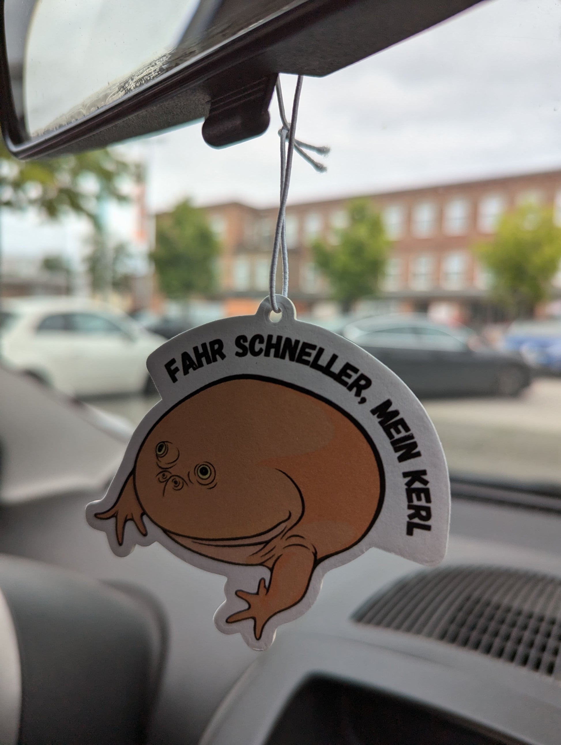 Auto Duftbaum Mittwochsfrosch Nummer zwei hängt am Auto Rückspiegel.