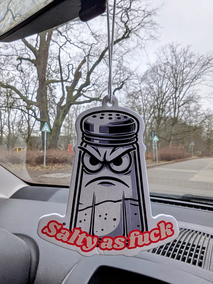 Auto Duftbaum in Form eines Comic-Salzstreuers mit grimmigem Gesicht und rotem Schriftzug „Salty as fuck“, Lufterfrischer fürs Auto mit witzigem Motiv, origineller Autoduftbaum als Spaß-Artikel und Geschenkidee.