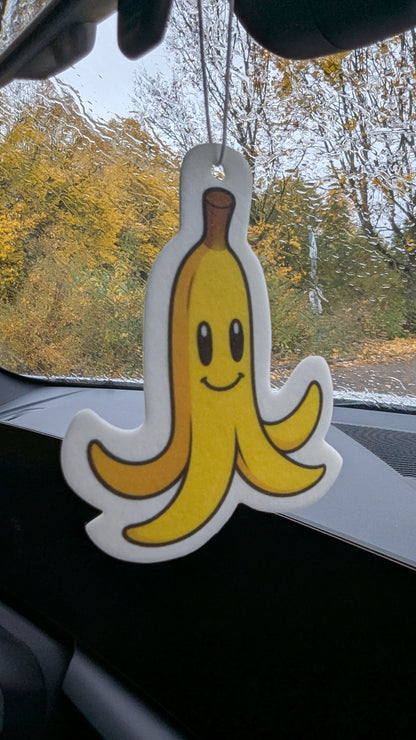 Gelbe Bananenschale mit Gesicht als lustiger Auto Duftbaum und Lufterfrischer am Rückspiegel aufgehängt