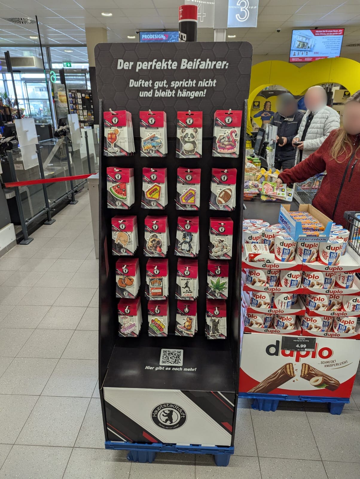 Verkaufsaufsteller mit verschiedenen Auto Duftbäumen im Supermarkt, Lufterfrischer fürs Auto in vielen Motiven wie Tiere, Symbole und Sprüche, originelle Autoduftbäume als Geschenkidee und Mitnahmeartikel an der Kasse.
